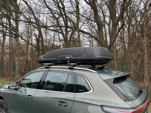 Thule Dachbox "Force XT Gr. XL" Dachbox auf einem grauen Auto, geparkt unter Bäumen.
