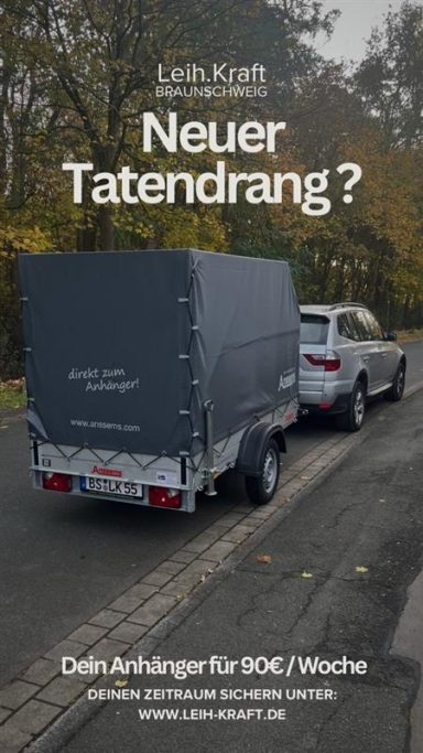 Ein Fahrzeug mit Anhänger auf einer Straße, umgeben von Bäumen im Herbst.