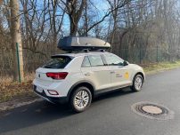 Thule Dachbox "Force XT Gr. L " Volumen 450 liter84x46 cm Ein weißer SUV mit Dachbox steht an einer Straße, umgeben von Bäumen.