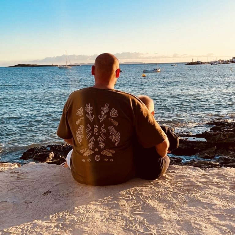Mann sitzt am Ufer und blickt auf das Wasser bei Sonnenuntergang.