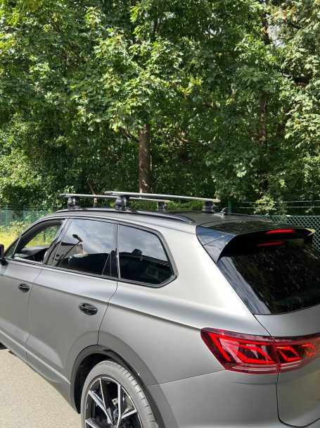 Thule Dachgepäckträger Silberner SUV mit Dachgepäckträger, parkend in einer grünen Umgebung.