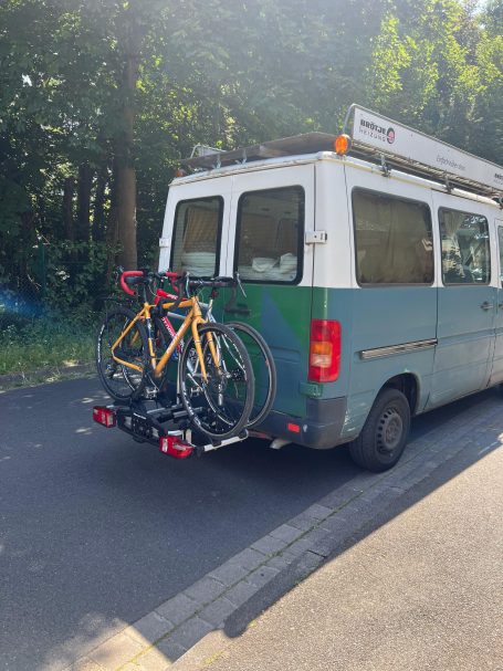 Fahrradträger "2x 30kg pro Bike" Blauer Lieferwagen mit zwei Fahrrädern auf einem Trägersystem hinten.