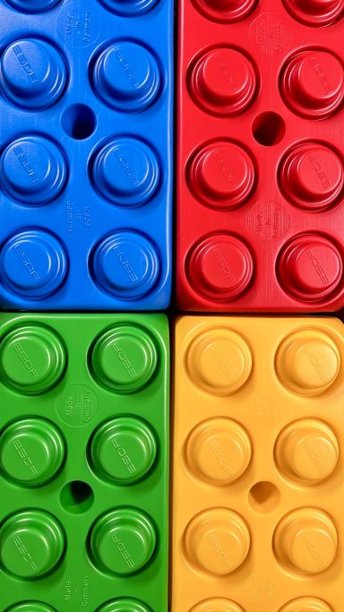 Bunte LEGO-Steine in Blau, Rot, Grün und Gelb angeordnet.