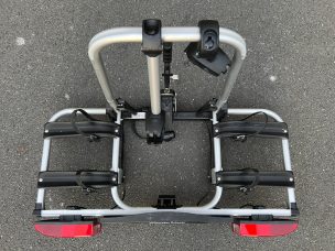 Fahrradträger mit zwei Halterungen und rotem Rücklicht auf grauem Boden.