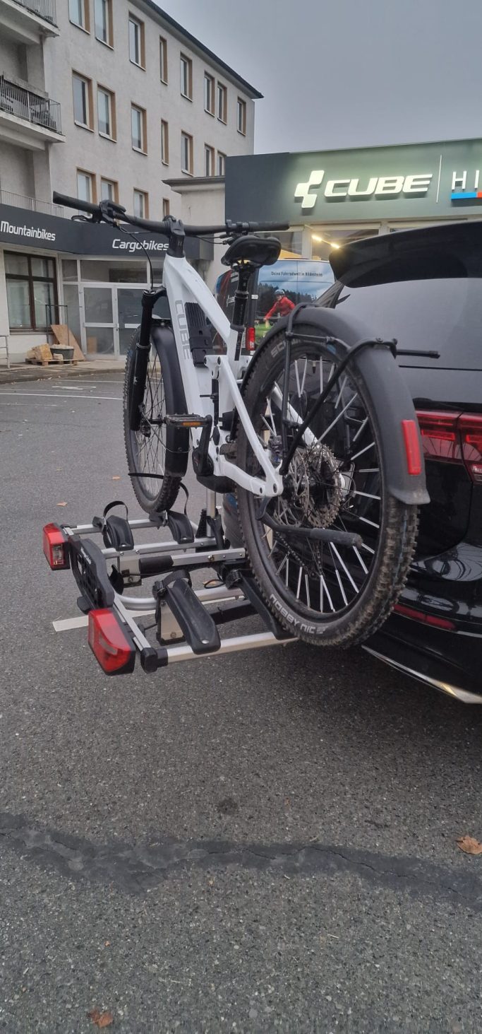 Ein Fahrradträger mit einem montierten E-Bike auf der Rückseite eines Autos.