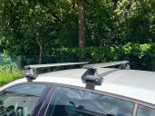 "Thule Clamp" Geeignet für Fahrzeuge ohne Dachreling Dachträger auf einem weißen Auto, montiert auf einer grünen Wiese.