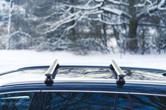 Dachträger eines Autos auf verschneitem Gelände mit Bäumen im Hintergrund.