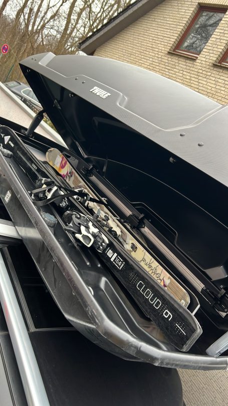 Dachbox auf einem Auto mit geöffnetem Deckel und Gepäck im Inneren.
