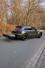 Thule Arcos XL "450l" Sportliches schwarzes Auto mit abnehmbarem Heck, auf einer kurvenreichen Straße umgeben von Bäumen.