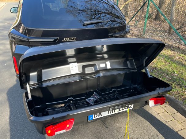 Kofferraum eines schwarzen Autos mit offenem Deckel, leer und gut sichtbar.