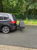 Thule Heckbox Onto Schwarzer SUV mit montierter Fahrradträger am Heck, parkend auf einer Straße.