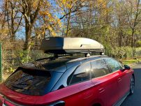 Thule Dachbox "Force XT Gr. XL " Außenmaße: 210x86x44 cm Roter Kombiwagen mit Dachbox, umgeben von Bäumen im herbstlichen Umfeld.
