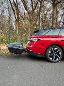 Thule Heckbox Arcos Gr. M Roter SUV mit schwarzem Anhänger, geparkt in einer Waldumgebung.