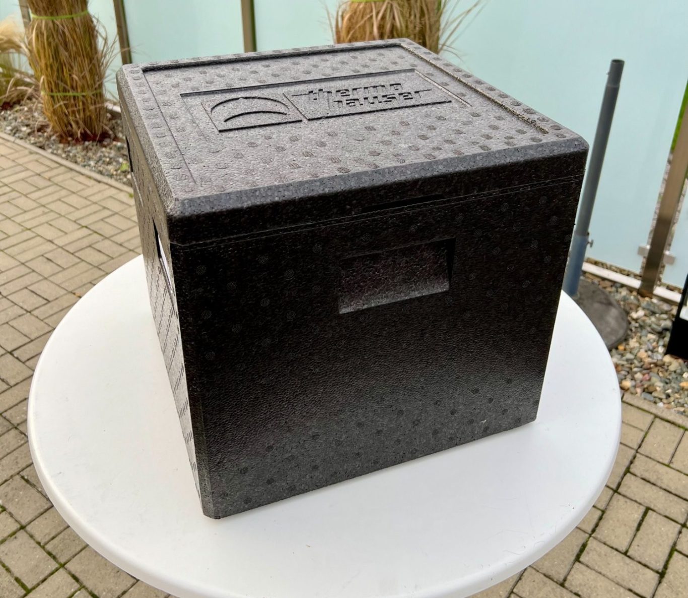 Schwarze, quadratische Box mit einer Grifföffnung auf der Vorderseite.